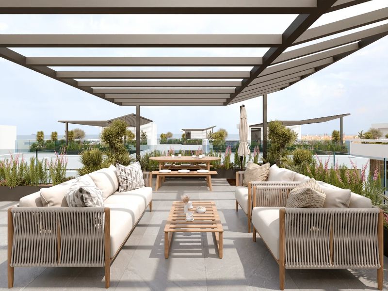 Shaded patio with white outdoor sofas and dining set beneath a slatted pergola